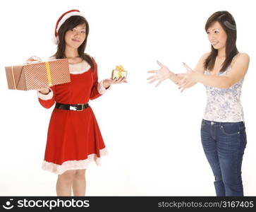 Young woman in a Santa costume holding Christmas gifts with her twin reaching towards her