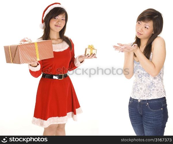 Young woman in a Santa costume holding Christmas gifts with her twin standing beside her
