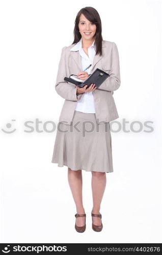 Young woman in a skirt suit writing in a personal organizer