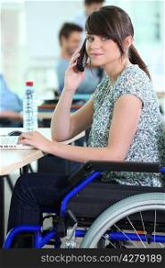 Young woman in a wheelchair at her desk