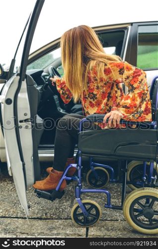 Young woman in a wheelchair getting on the car. Woman in wheelchair getting on car