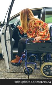 Young woman in a wheelchair getting on the car. Woman in wheelchair getting on car