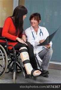 young woman in a wheelchair with leg in plaster. in an interview with the doctor
