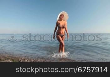 young woman in a white hat comes out of sea