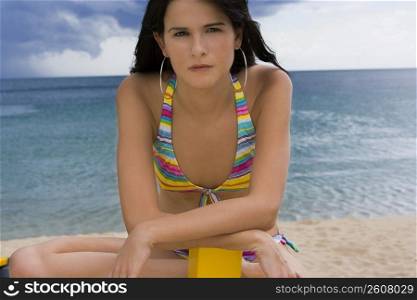 Young woman in bathing suit sitting on wooden boat on beach