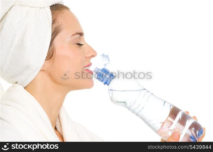 Young woman in bathrobe drinking from bottle with water