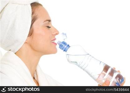 Young woman in bathrobe drinking from bottle with water