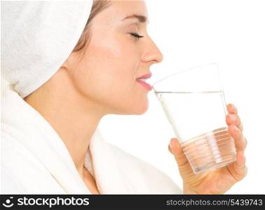 Young woman in bathrobe drinking water