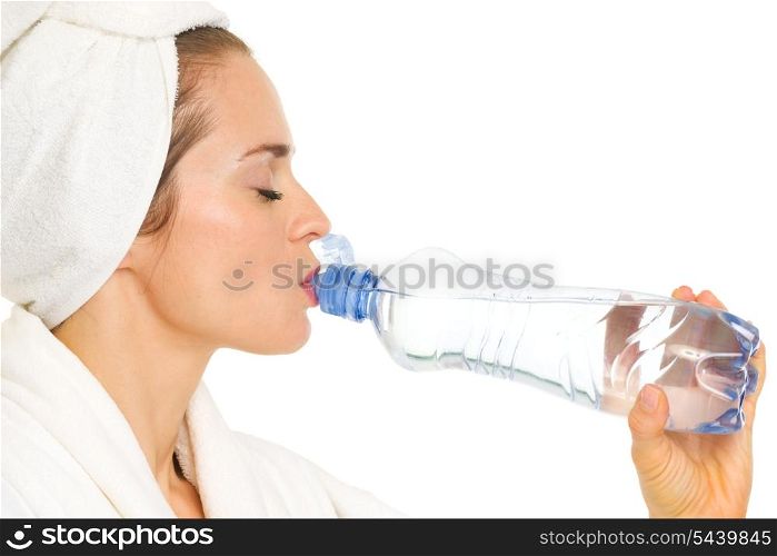 Young woman in bathrobe drinking water from bottle