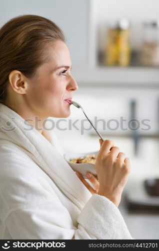 Young woman in bathrobe enjoying breakfast in morning