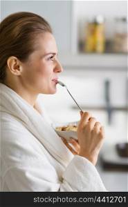 Young woman in bathrobe enjoying breakfast in morning