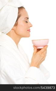 Young woman in bathrobe enjoying cup of tea