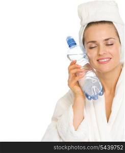 Young woman in bathrobe holding bottle with water