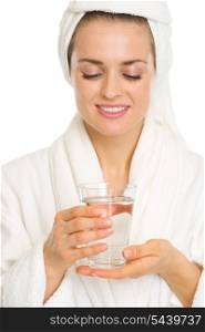 Young woman in bathrobe holding glass with water