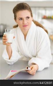 Young woman in bathrobe with milk and magazine