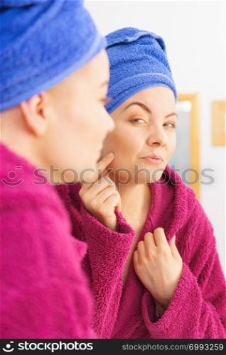 Young woman in bathroom after taking shower feeling clean and relaxed wearing towel and bathrobe investigating her skin condition.. Woman in towel after shower
