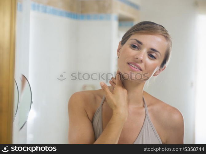 Young woman in bathroom checking skin condition