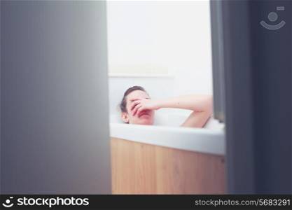 Young woman in bathtub is being watch through the half open door