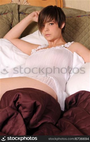 Young woman in bed in a white negligee