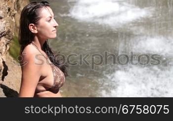 young woman in bikini resting by the waterfall