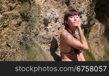Young woman in bikini washing the body by the waterfall
