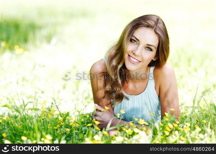 young woman in blue dress lying on grass. beautiful young woman in blue dress lying on grass
