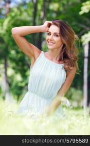 young woman in blue dress sitting on grass. beautiful young woman in blue dress sitting on grass