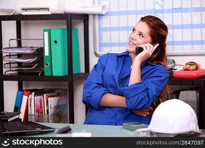 Young woman in blue overalls on the telephone in a depot