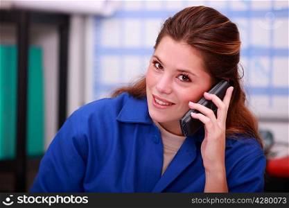 Young woman in blue overalls on the telephone in a depot
