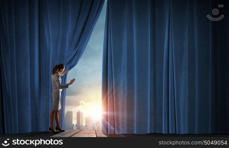 Young woman in business suit opening color curtain of stage. Open new opportunities