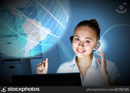 Young woman in business wear in headset working with computer