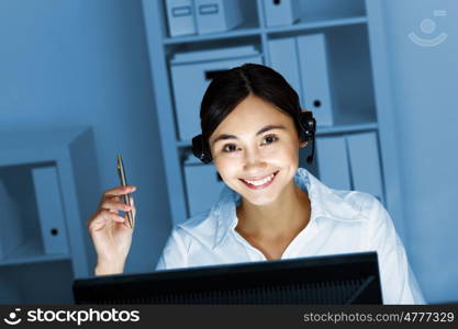 Young woman in business wear in headset working with computer