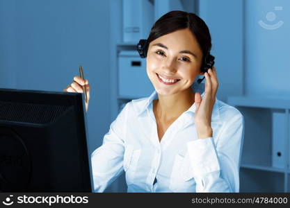 Young woman in business wear in headset working with computer