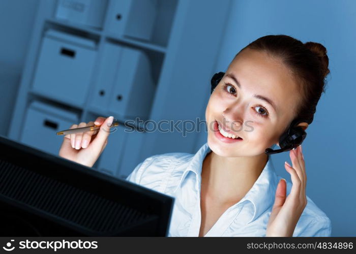 Young woman in business wear in headset working with computer