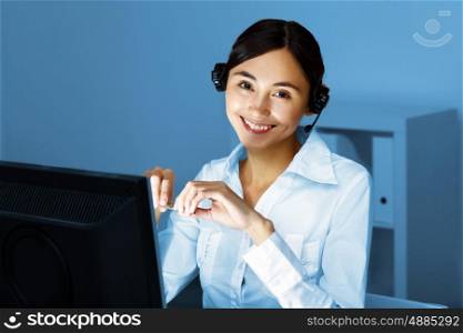 Young woman in business wear in headset working with computer