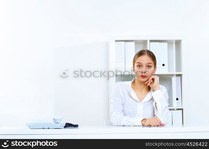 Young woman in business wear sitting with a phone in office