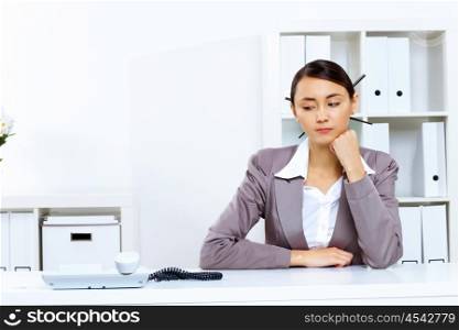 Young woman in business wear sitting with a phone in office