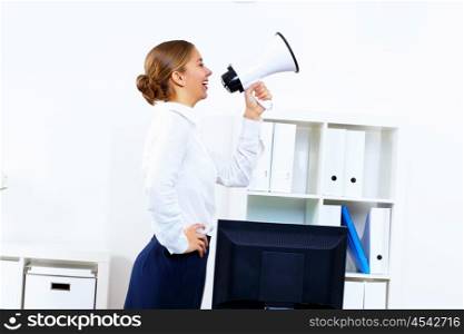 Young woman in business wear with megaphone in office
