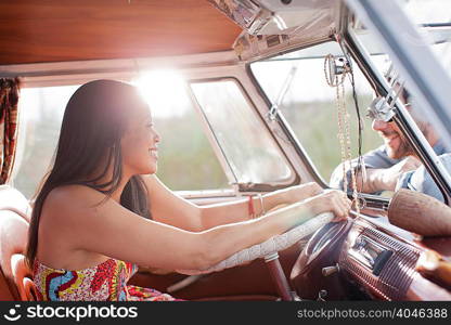 Young woman in camper van and smiling at boyfriend