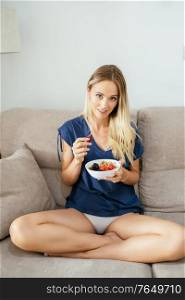 Young woman in casual clothes eating an vegan appetizer with nuts, raspberries and blackberries. Concept of healthy diet.. Caucasian girl eating an vegan appetizer with nuts, raspberries and blackberries.