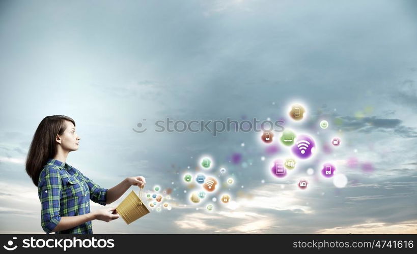 Young woman in casual holding yellow bucket with icons