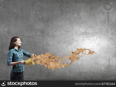 Young woman in casual holding yellow bucket with splashes. Add some color