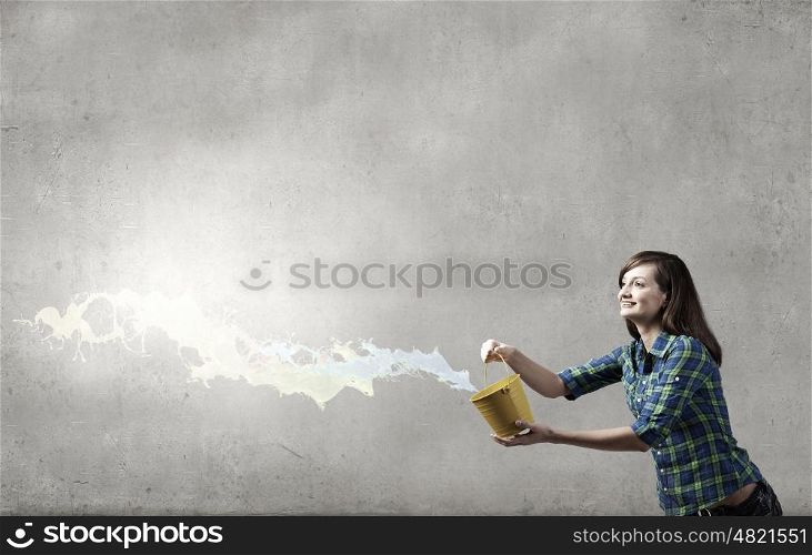 Young woman in casual holding yellow bucket with splashes. Add some color