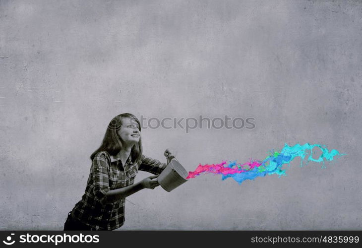 Young woman in casual holding yellow bucket with splashes. Add some color