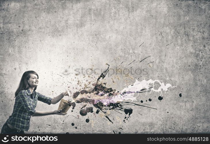 Young woman in casual holding yellow bucket with splashes. Add some color