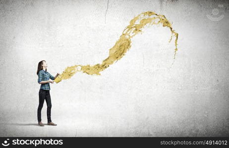 Young woman in casual holding yellow bucket with splashes. Add some color