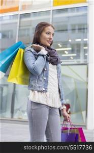 Young woman in casuals carrying shopping bags outdoors