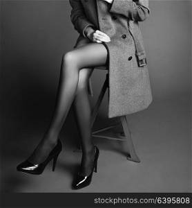 Young woman in coat with beautiful feet. Beautiful long legs. Autumn coats and shoes. Girl in stockings. Black and White photo