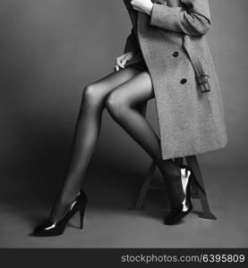 Young woman in coat with beautiful feet. Beautiful long legs. Autumn coats and shoes. Girl in stockings. Black and White photo