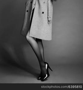 Young woman in coat with beautiful feet. Beautiful long legs. Autumn coats and shoes. Girl in stockings. Black and White photo